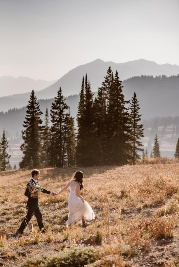 Couple walking through a meadow on their wedding day in Colorado