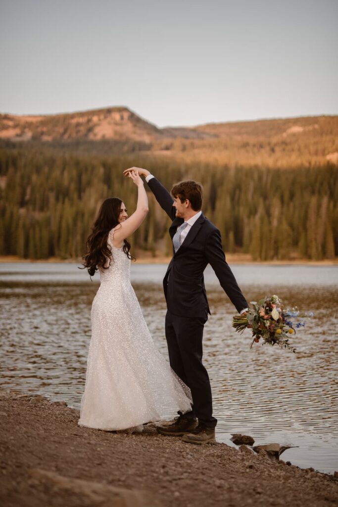 Couple shares wedding day first dance on the shore of a lake at sunset