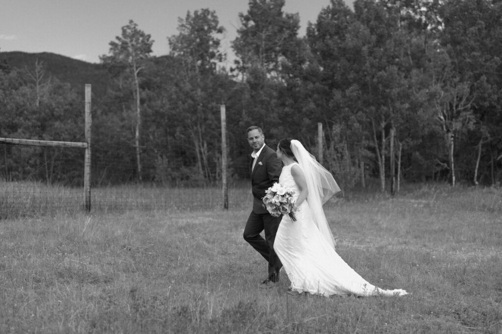 Bride and her father walking through a meadow