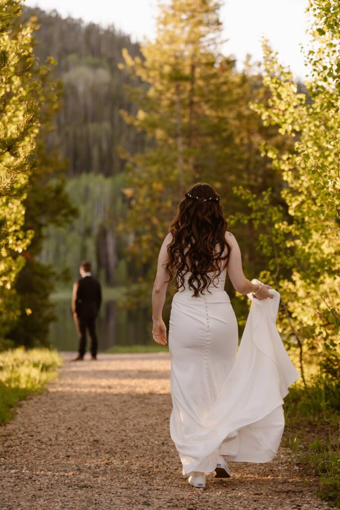 Bride walking to her groom for a first look by the lakeshore