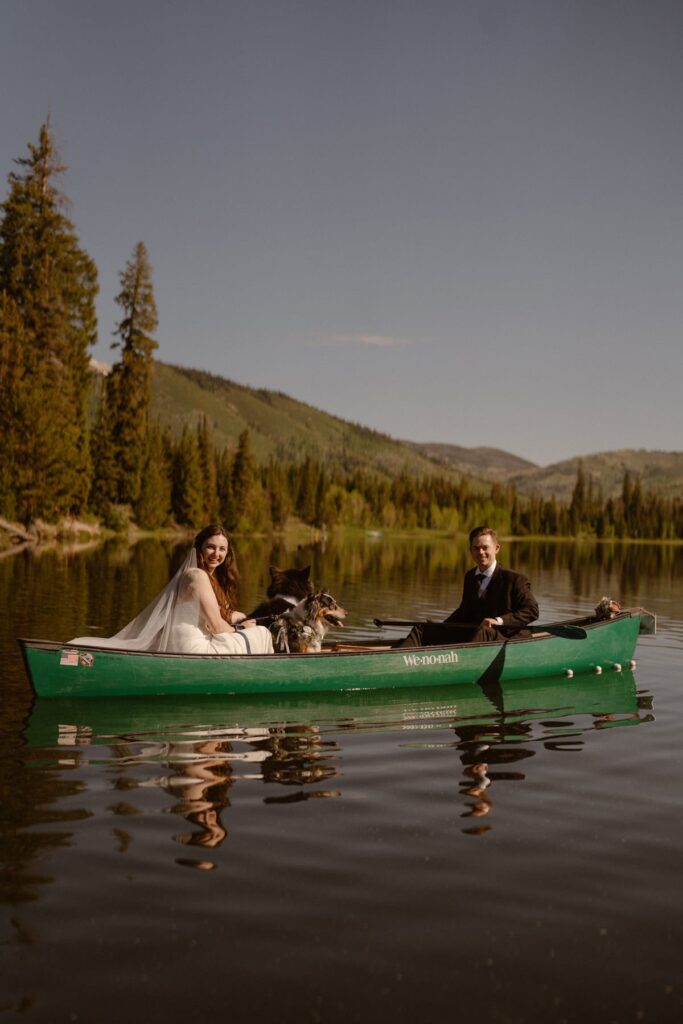 Bride and groom in a canoe on a mountain lake with their dogs