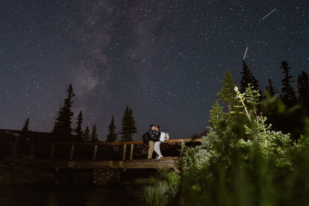 Couple kissing under a starry night sky on their wedding day before the sun comes up