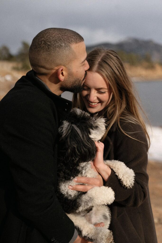 Couple kissing while holding their dog