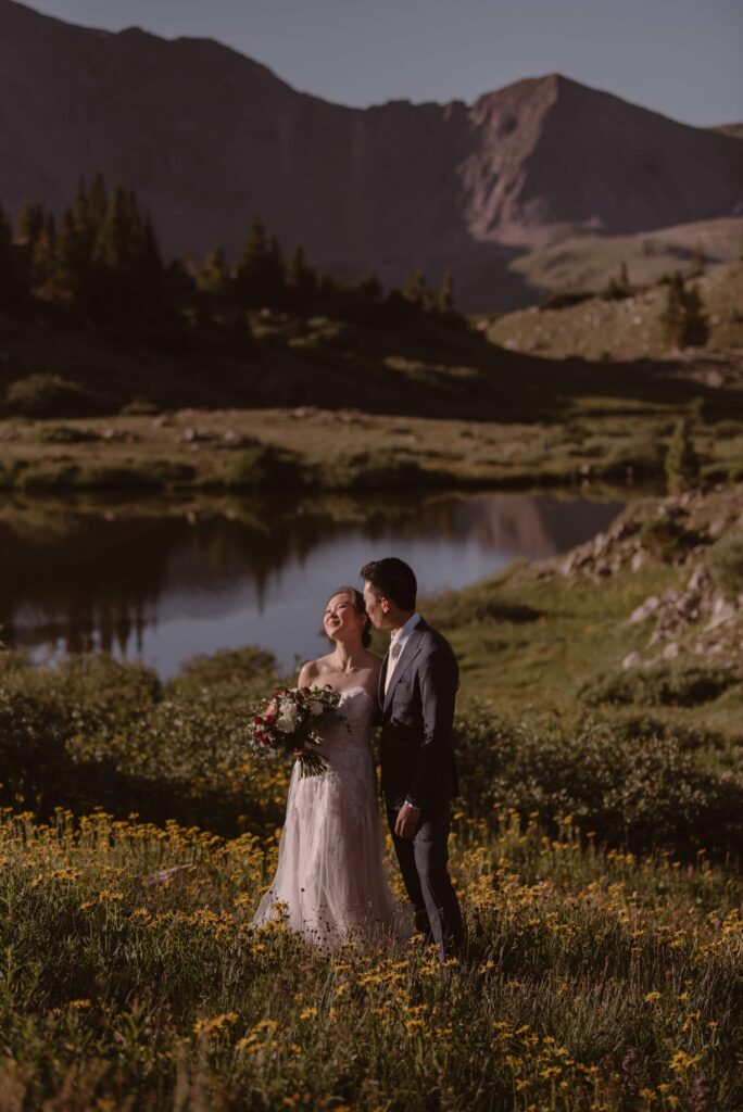 Bride and groom photos in the mountains with wildflowers and a lake