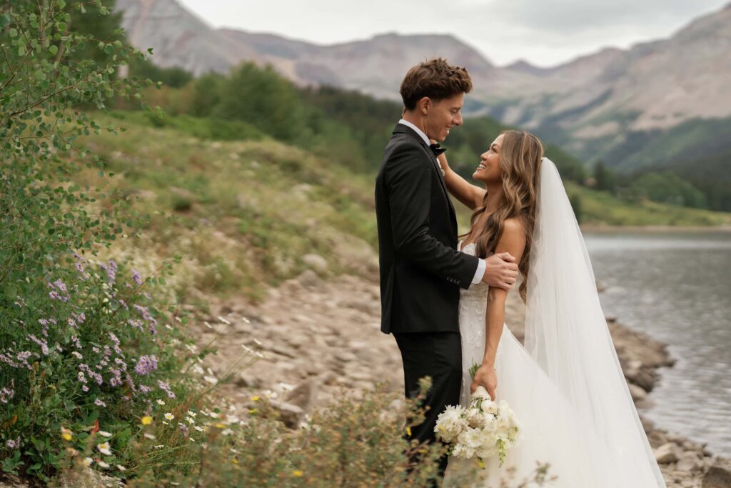 Bride and groom photos at lake in Telluride with wildflowers