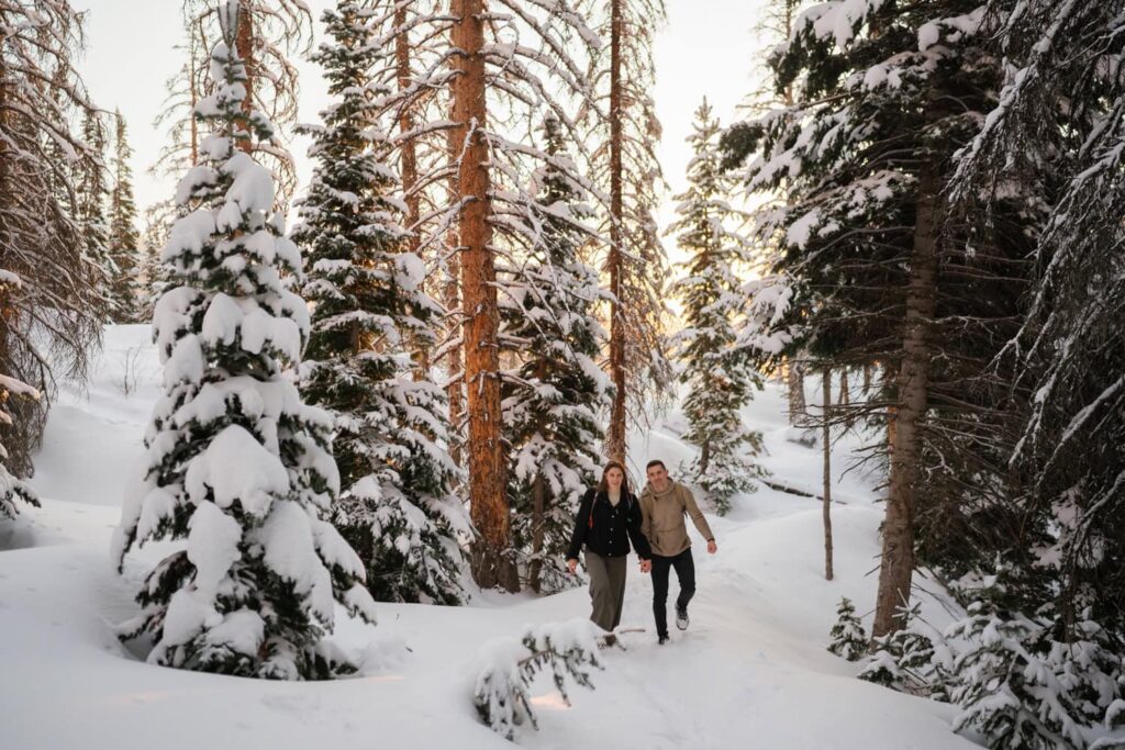 Couple hiking through snowy forest on way to Dream Lake