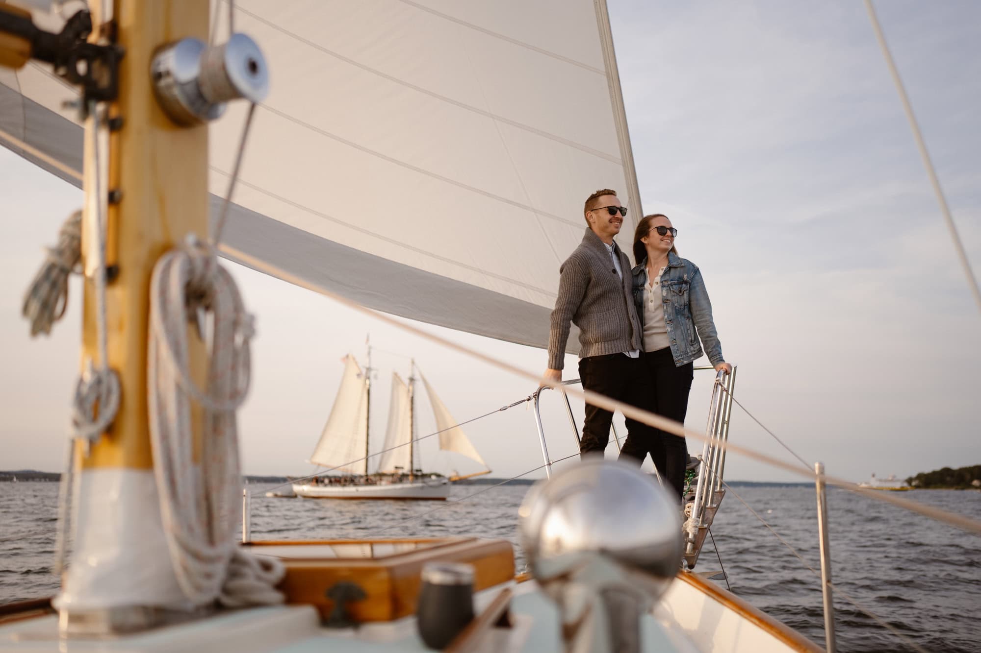 Romantic couples photos on a sailboat with other boats in the distance