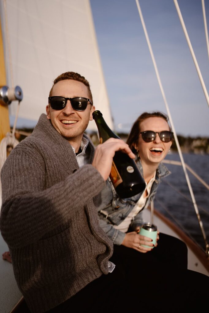 Couple drinking champagne and laughing on a sailboat