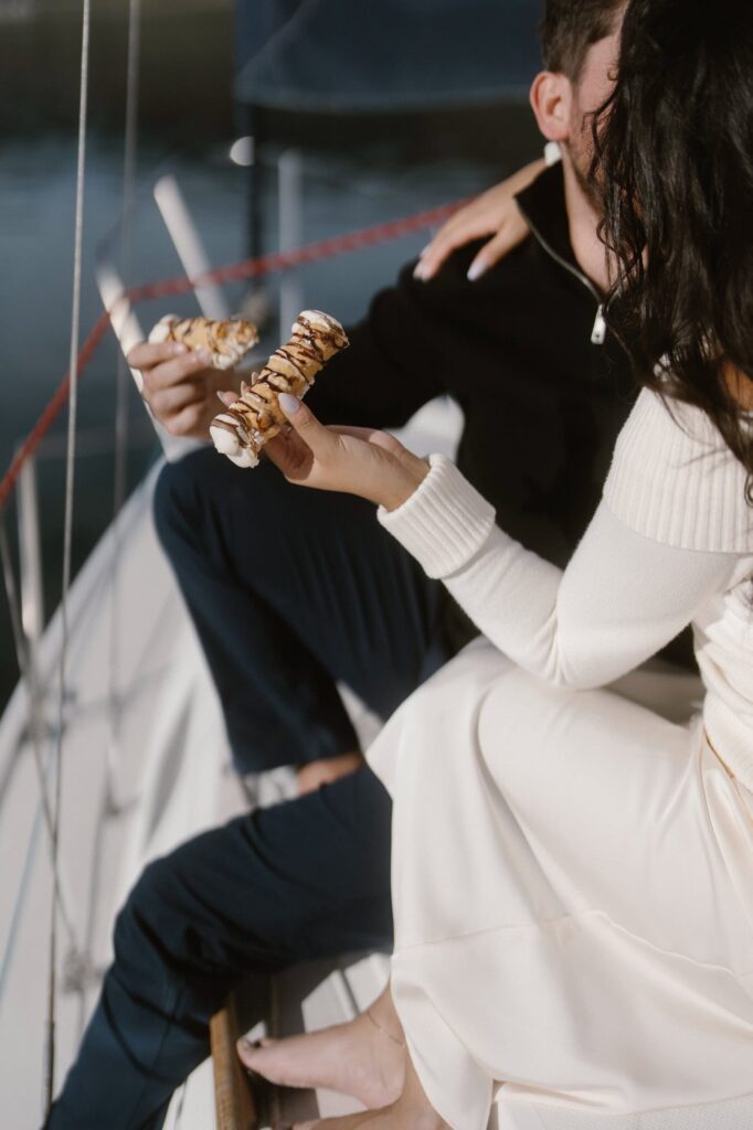 Couple eating cannolis on a sailboat