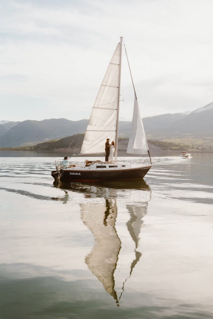 Sailboat engagement photos at sunset on glassy water