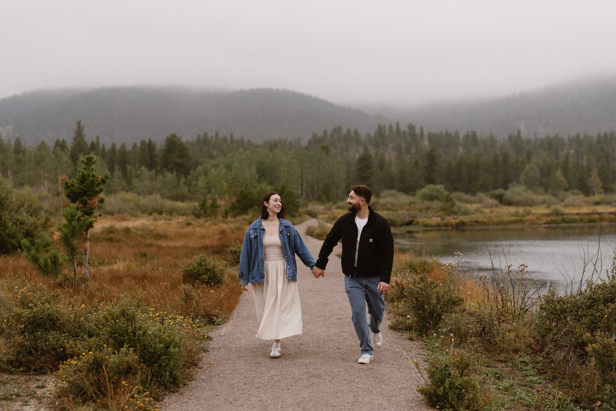 Couple running down dirt path at Lily Lake in Estes Park