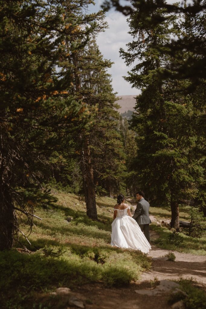 Bride and groom hiking down a mountain trail in Grand Lake, Colorado