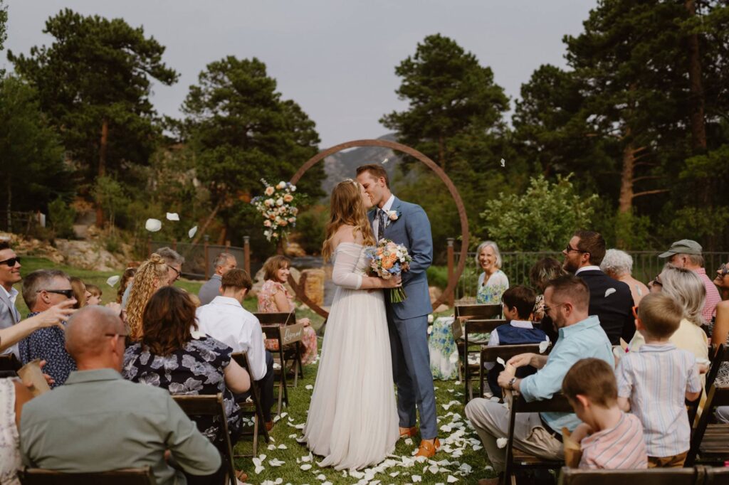 Just married kiss in front of round arch at The Landing at Estes Park