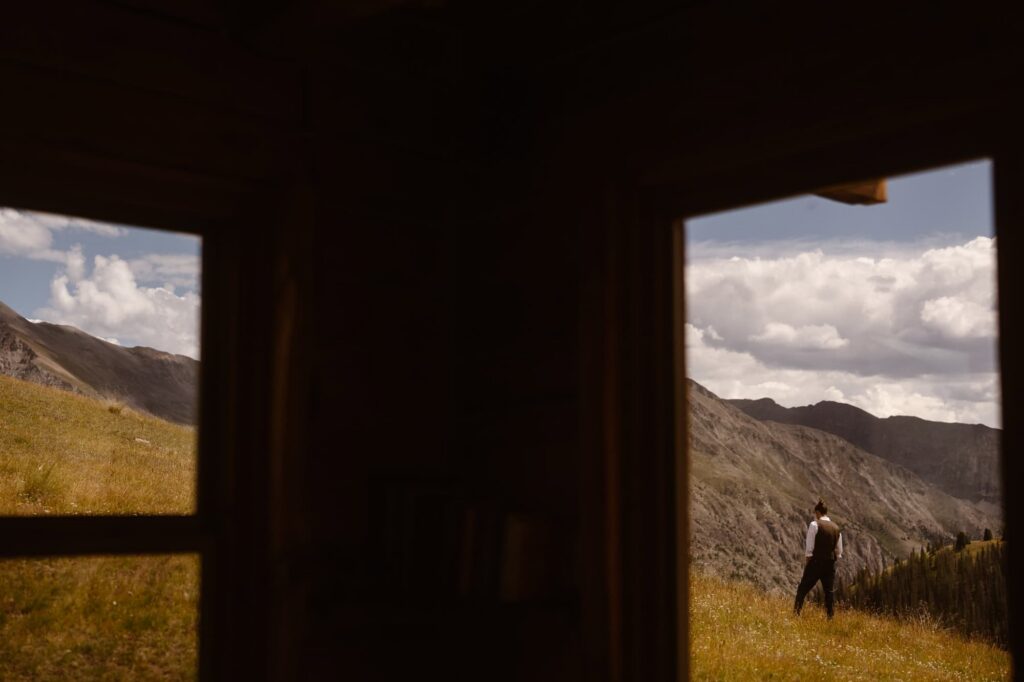 Groom outside of Colorado cabin in the mountains getting ready for first look