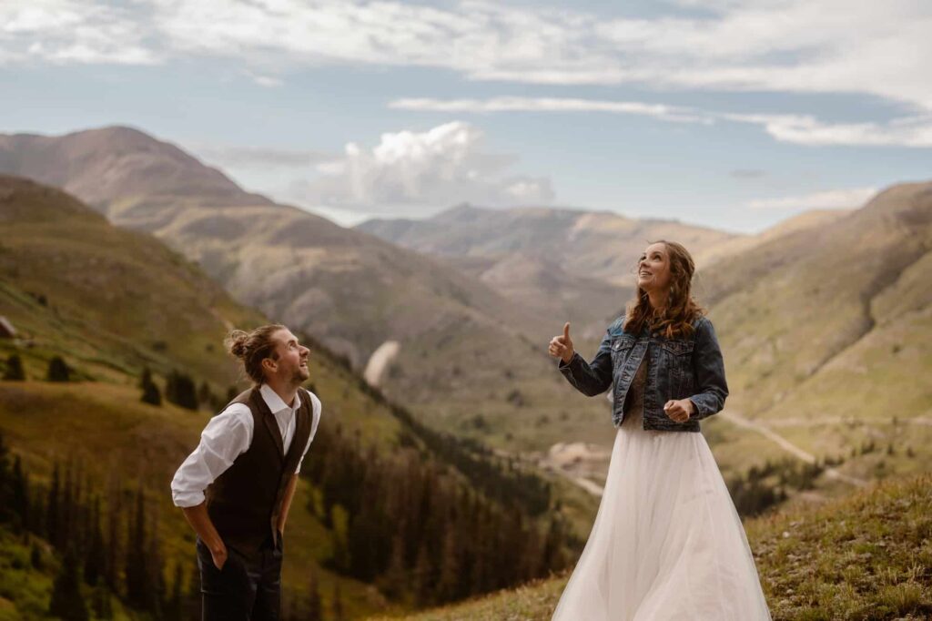 Bride and groom flipping a coin in the mountains