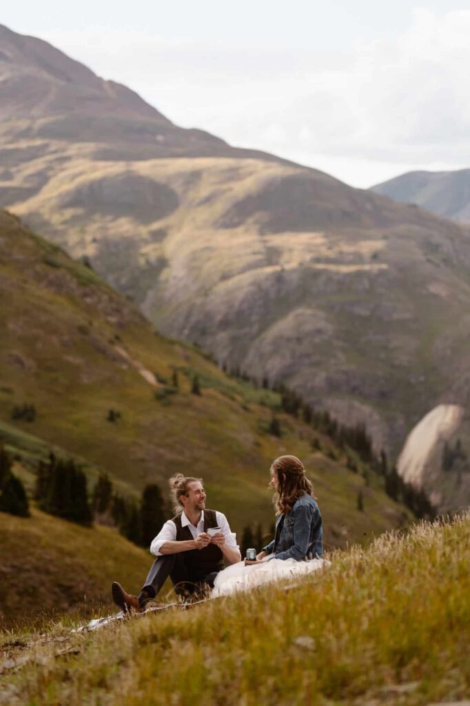 Bride and groom sitting on a mountainside reading wedding vows