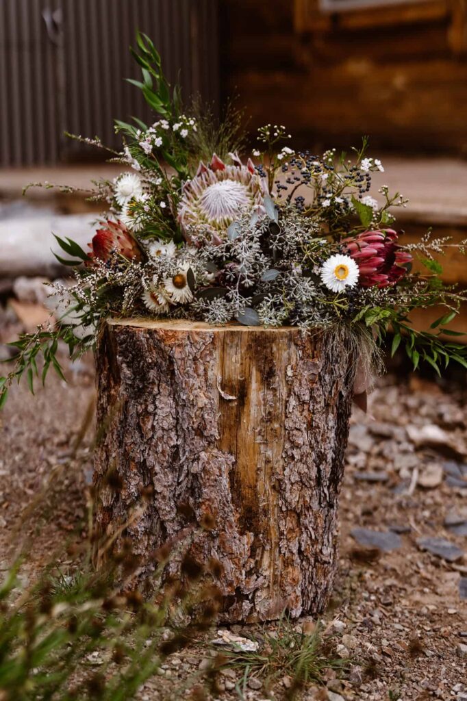 Wedding bouquet on top of a log outside of a cabin