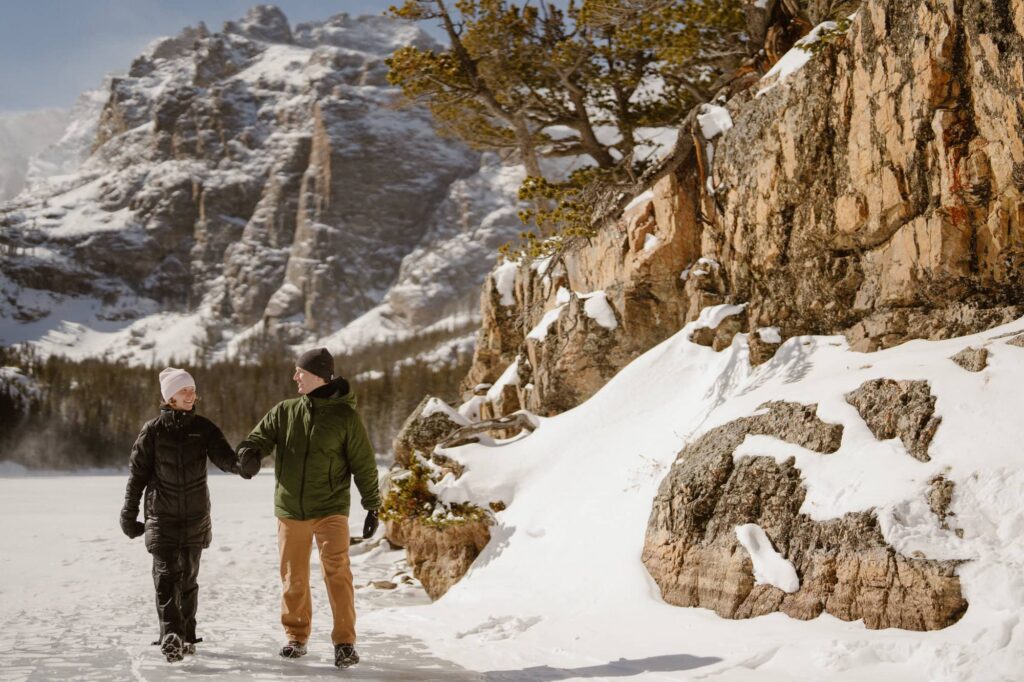 Couple walking through the snow in the mountains after a hiking proposal at The Loch