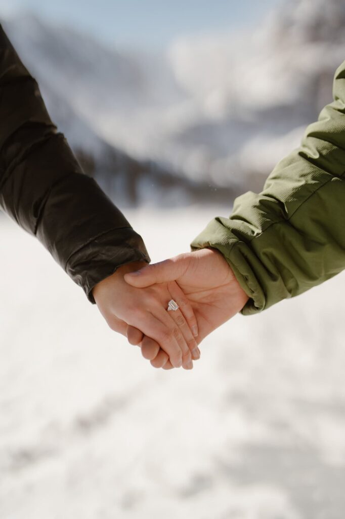 Couple holding hands with brand new engagement ring