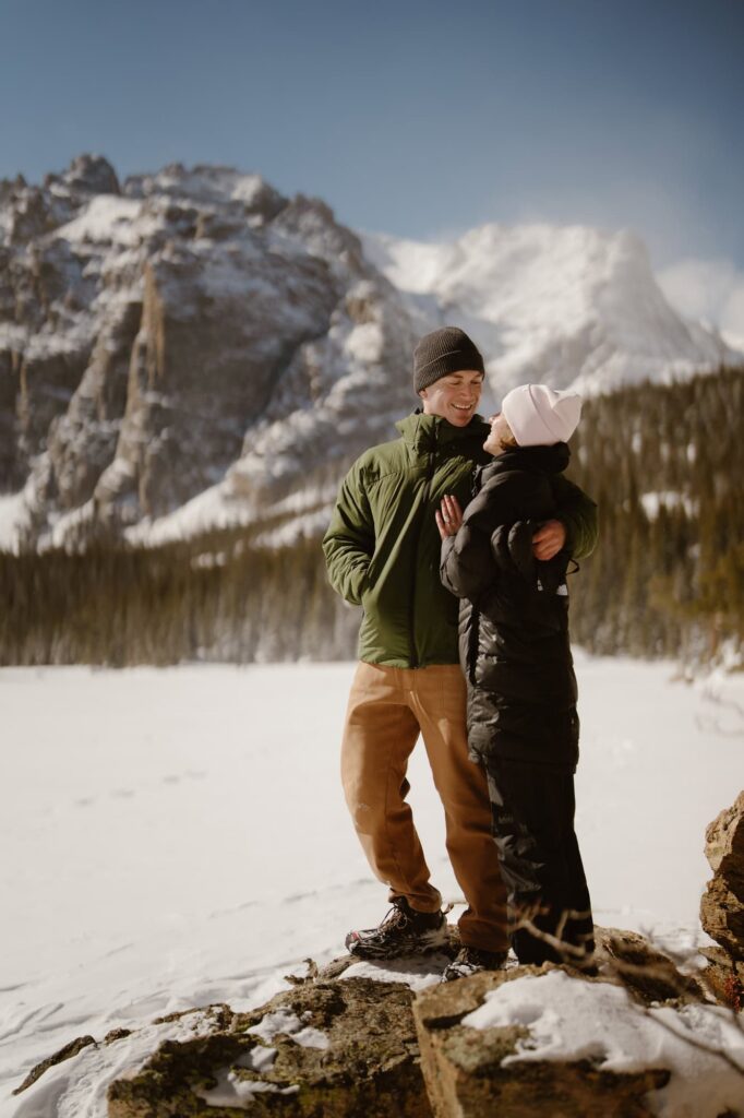 Couple standing on a rock at The Loch in Rocky Mountain National Park during winter
