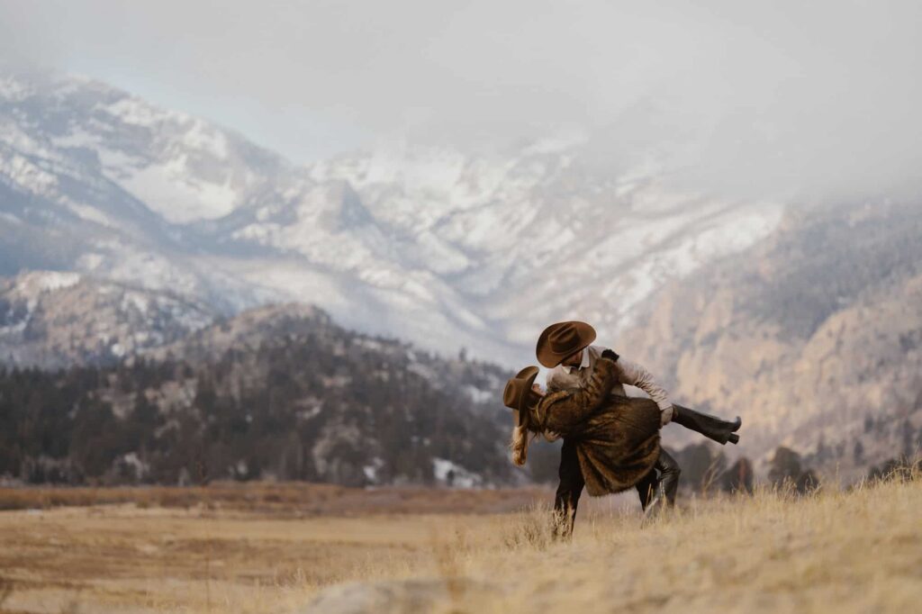 Couple dipping with cowboy hats in the mountains