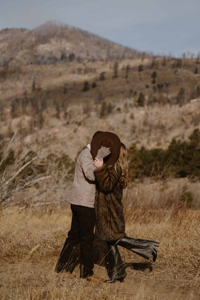 Couple kissing behind a cowboy hat