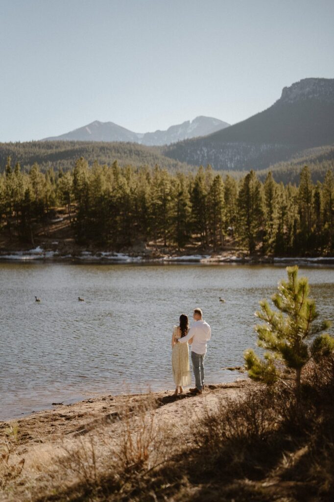 Couple on the shore of Lily Lake in Rocky Mountain National Park after surprise proposal