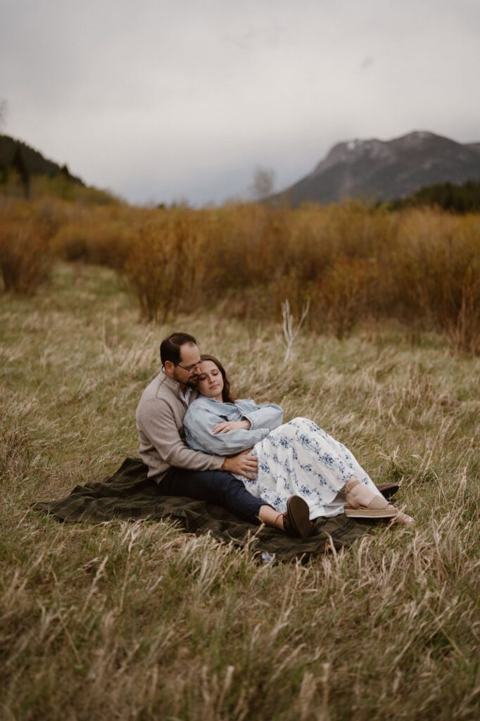 Couple snuggle on a blanket in a mountain meadow