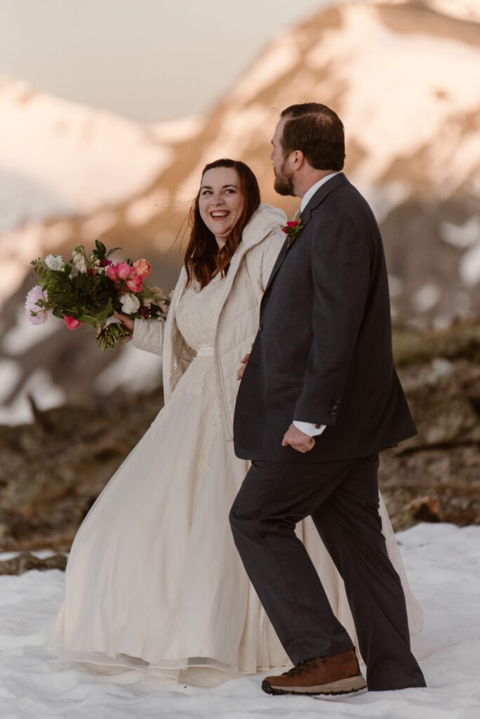 Documentary photos of couple laughing and walking on snow in the mountains on their wedding day