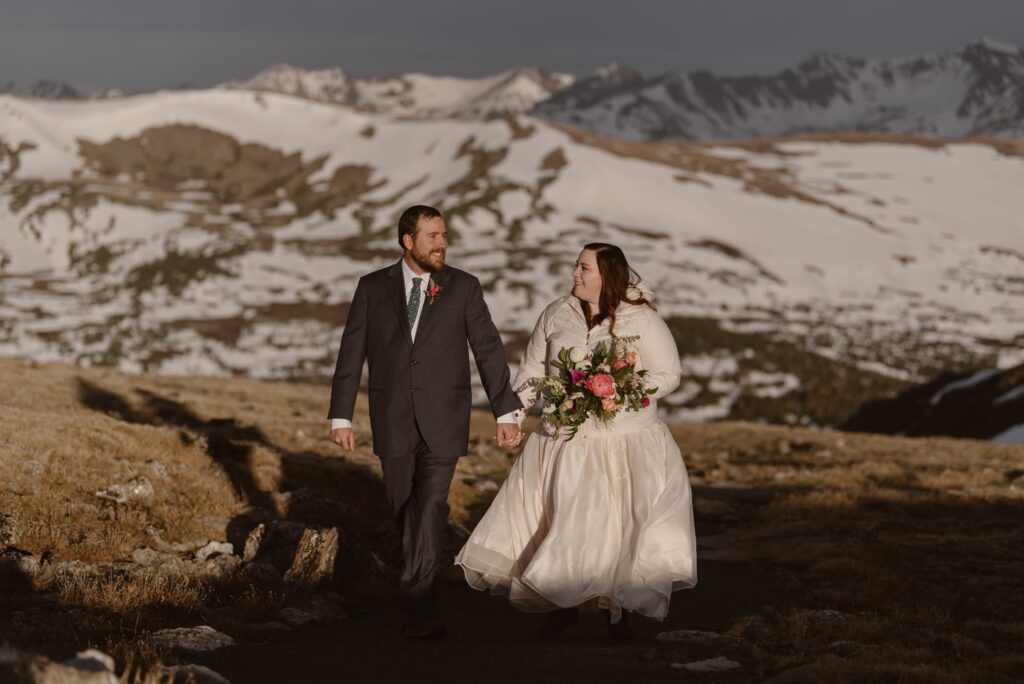 wedding couple walking hand in hand in the snowy mountains