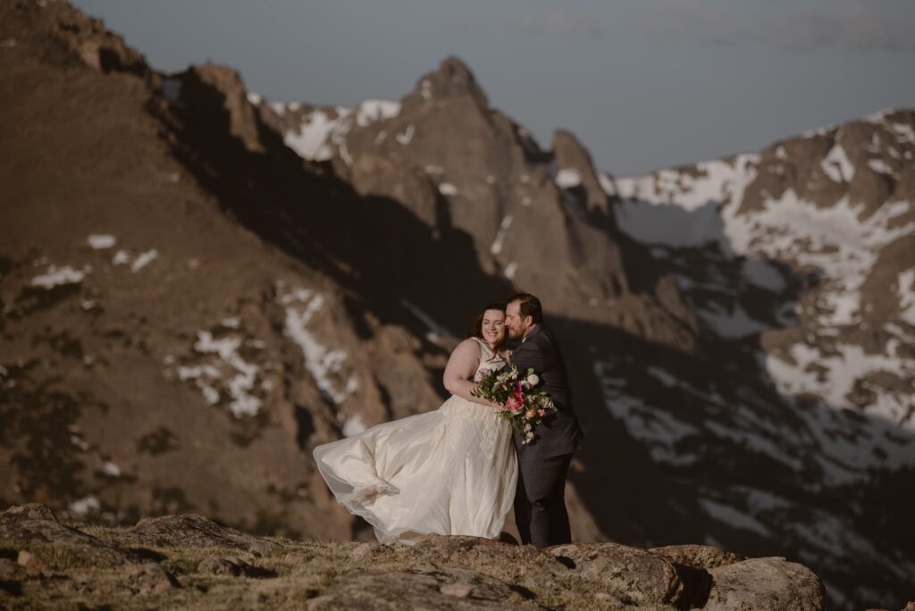 Wedding couple standing on snowy mountaintop in Rocky Mountain National Park