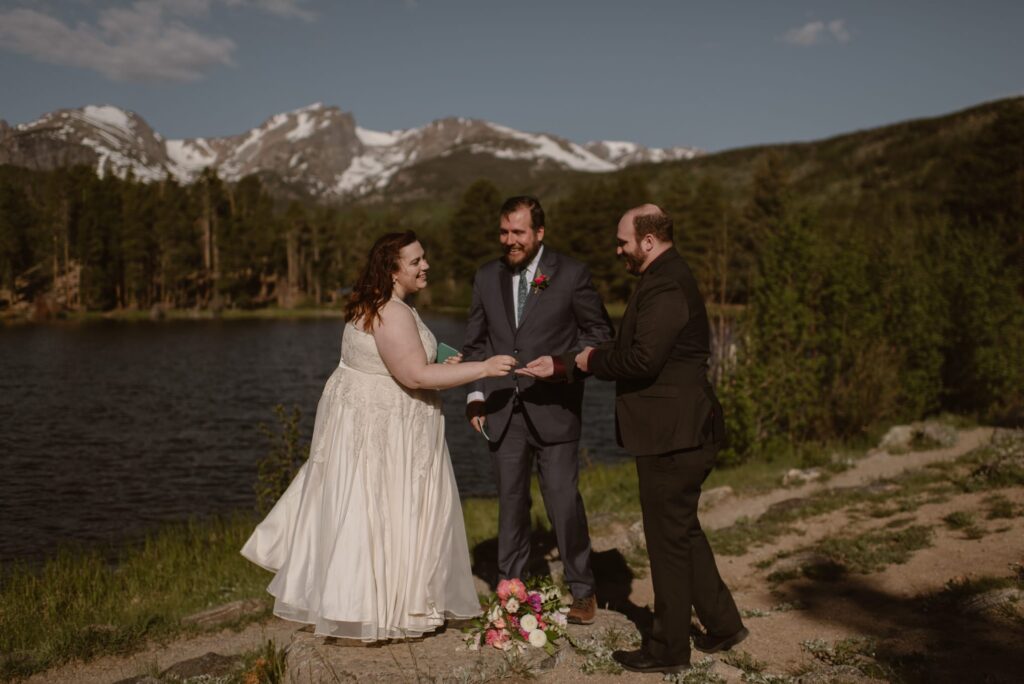 couple eloping on the shore of Sprague Lake in Rocky Mountain National Park with mountains in the distance