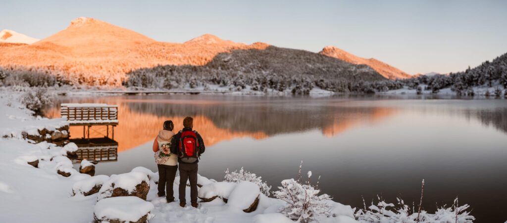 Couple standing at edge of Lily Lake with a snow covered scene about to have their wedding