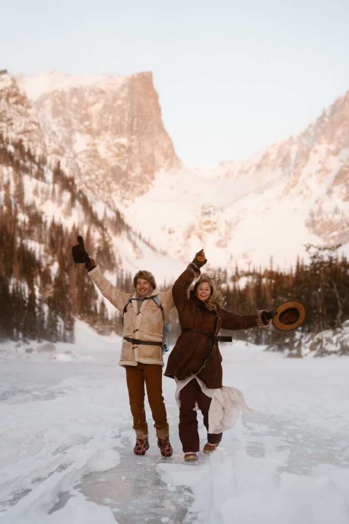 Couple with hands in the air at windy Dream Lake in Rocky Mountain National Park