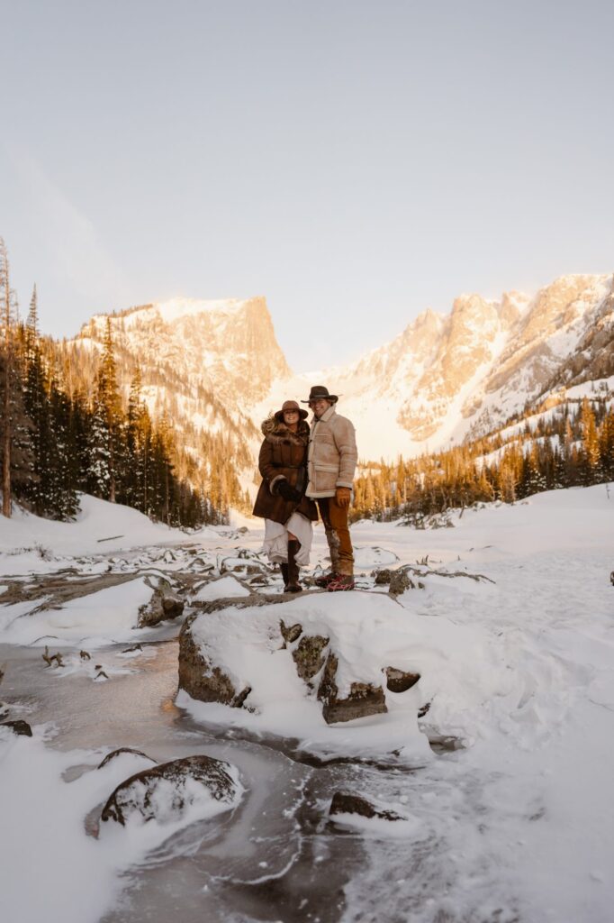 Couple standing on a rock on frozen Dream Lake in Estes Park during their lifestyle portrait photography session