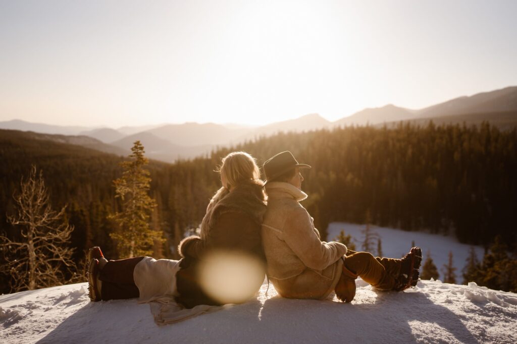 Couple sitting back to back in the mountains of Estes Park at sunrise