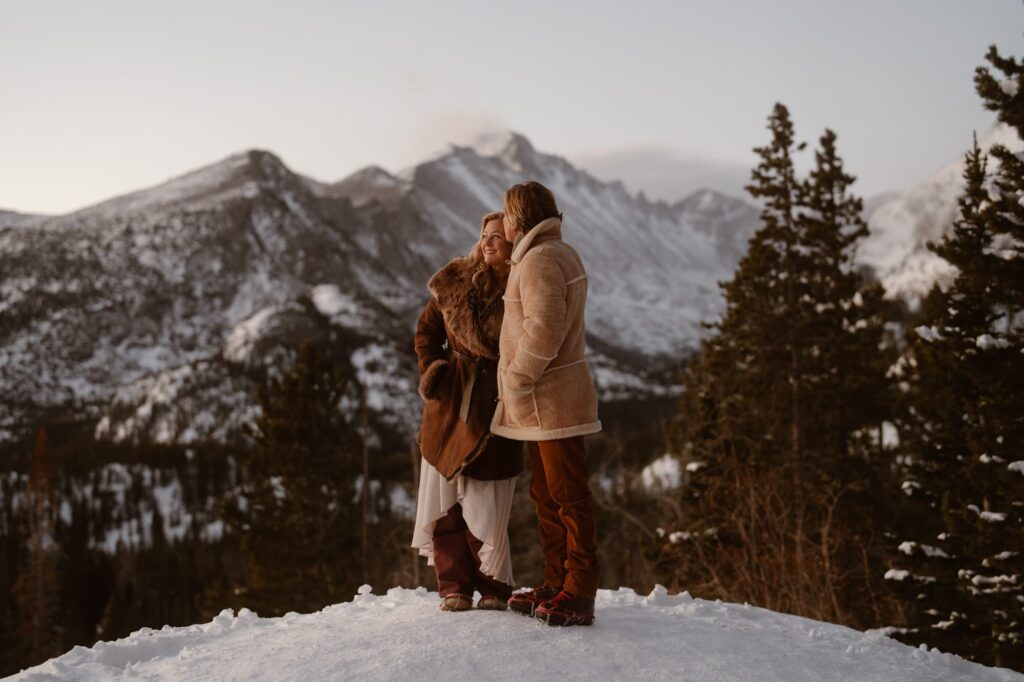 Husband kissing wife on the cheek overlooking the mountains in Estes Park