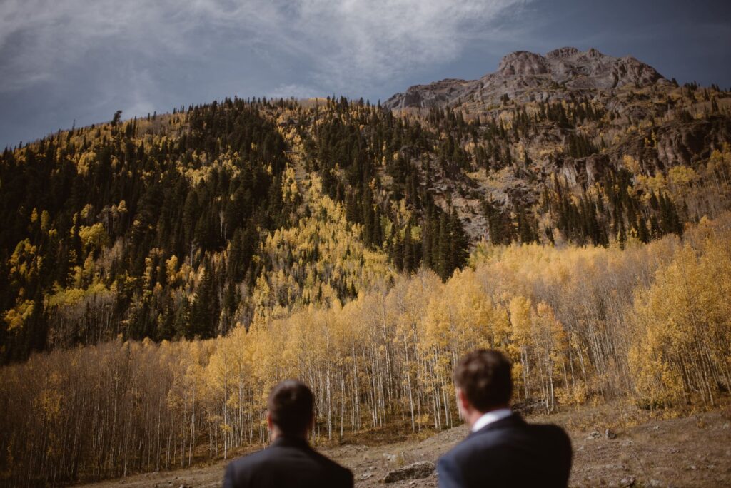 two grooms looking at fall foliage in colorado