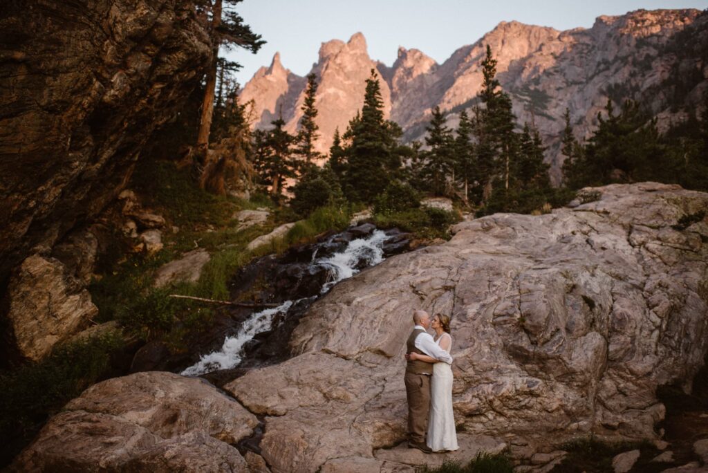 elopement photographer captures bride and groom in front of mountains and waterfall in Colorado