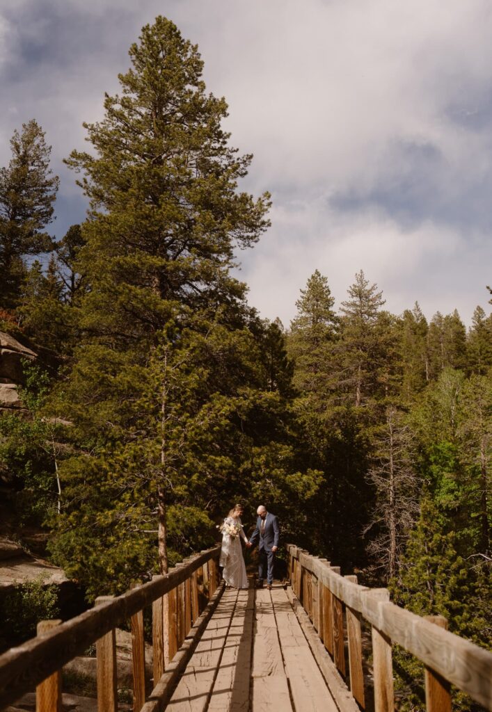 elopement couple walking across the bridge on Colorado hiking trail