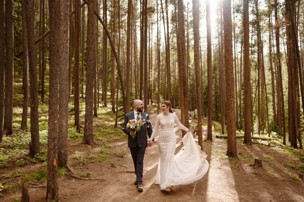 couple walking through lodge pole pine forest
