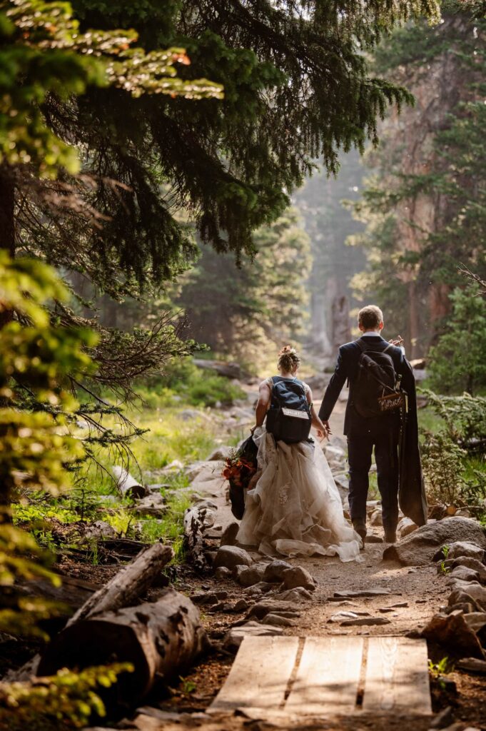 couple hiking through the woods in their wedding attire