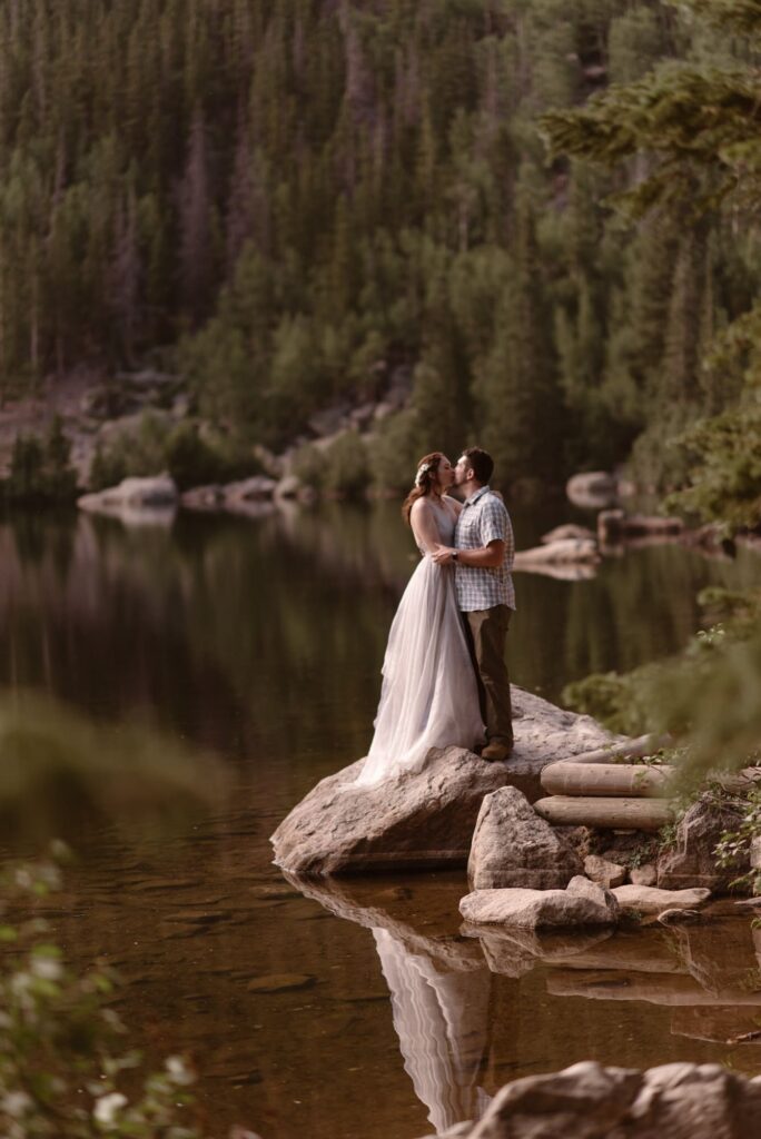 Couple kissing on a rock at the edge of Bear Lake in RMNP