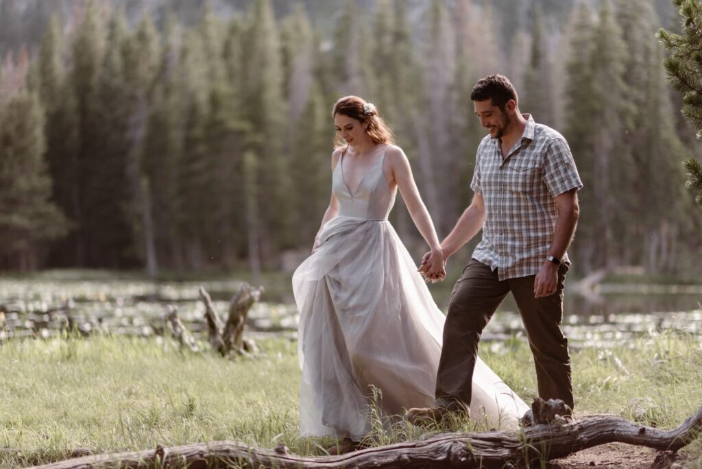 Couple walking with their wedding attire through a forest