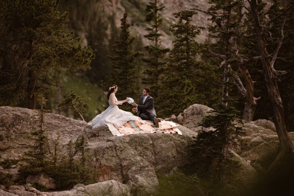 Couple sitting on a rock in the mountains having a picnic