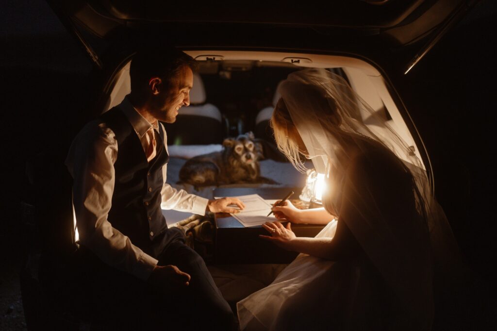 Couple signing their marriage license in the back of a glowing car