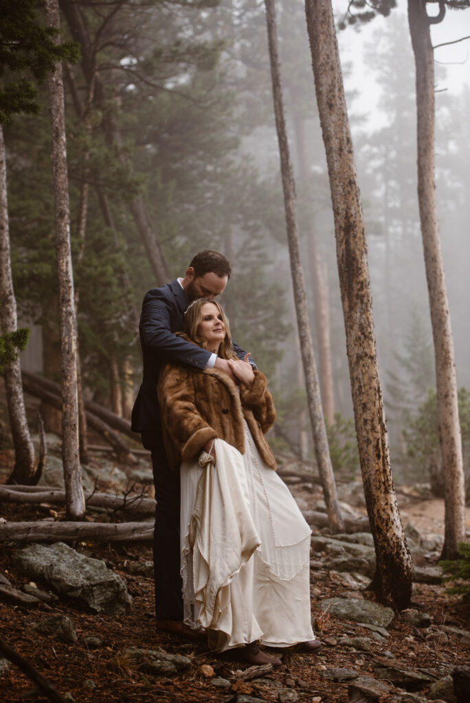 Couple cuddled in a moody and foggy forest