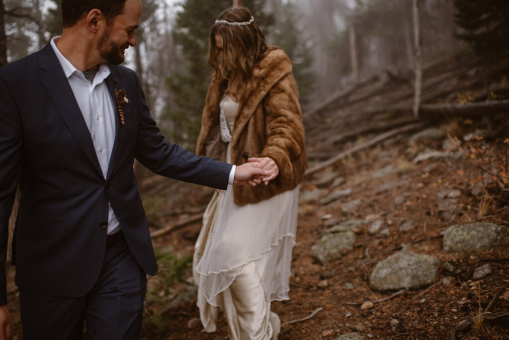 Couple walking through the foggy woods on their October wedding day in Estes Park