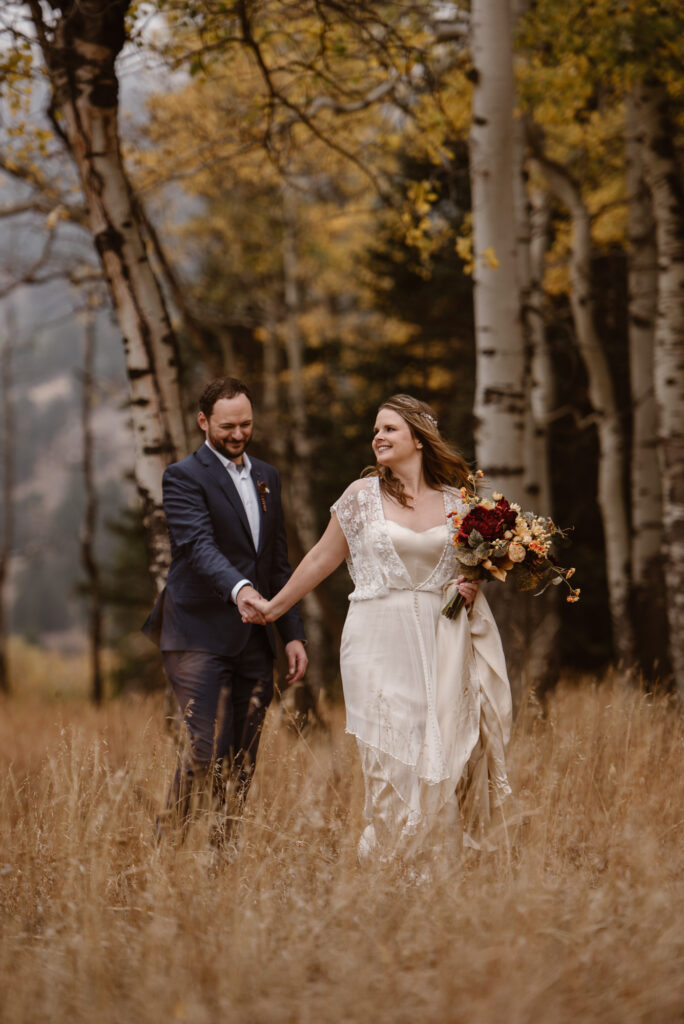 Couple smiling and walking through an aspen grove