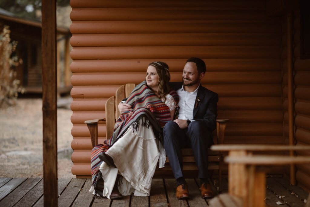 Couple snuggled up in a blanket on the porch of their cabin